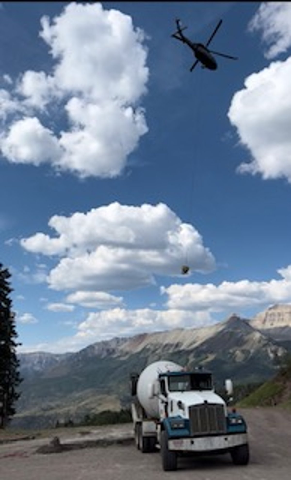 A Smith's Materials mixer truck with a helicopter lifting concrete to a mountain site